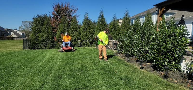 Riding mower cutting a striped green lawn