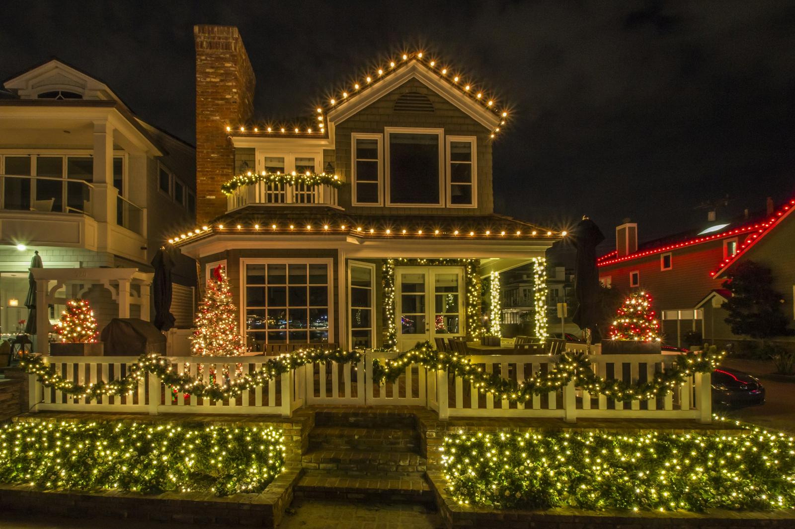 Two-story house lit with warm white Christmas lights along the roofline and porch